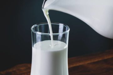 melk die uit een kan in een glas wordt geschonken