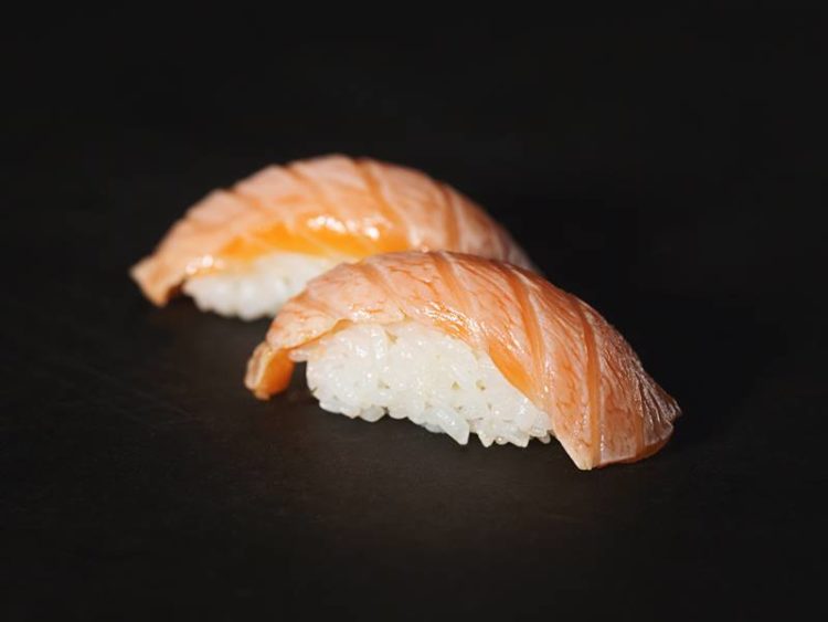 sushirijst met zalm tegen een zwarte achtergrond
