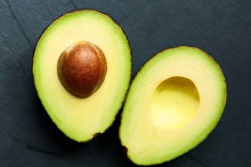 2 halve avocado's op zwarte leisteen achtergrond