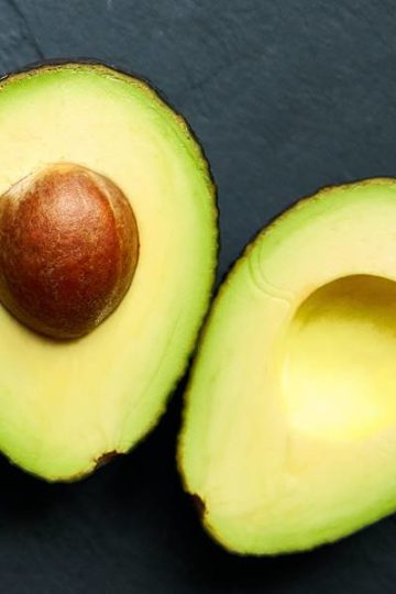 2 halve avocado's op zwarte leisteen achtergrond