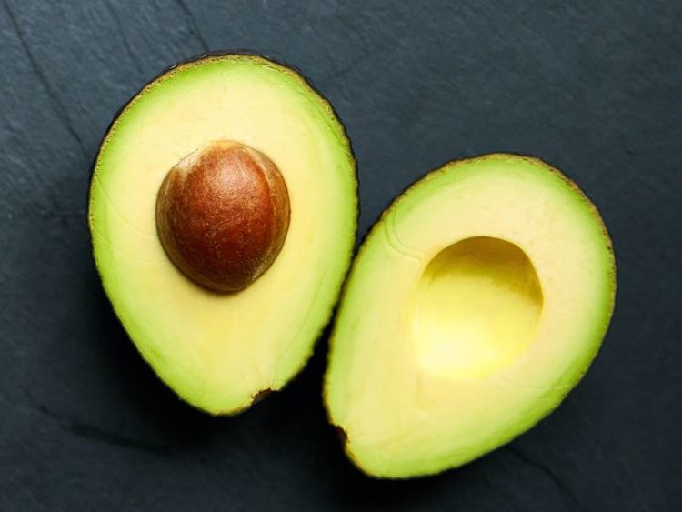 2 halve avocado's op zwarte leisteen achtergrond
